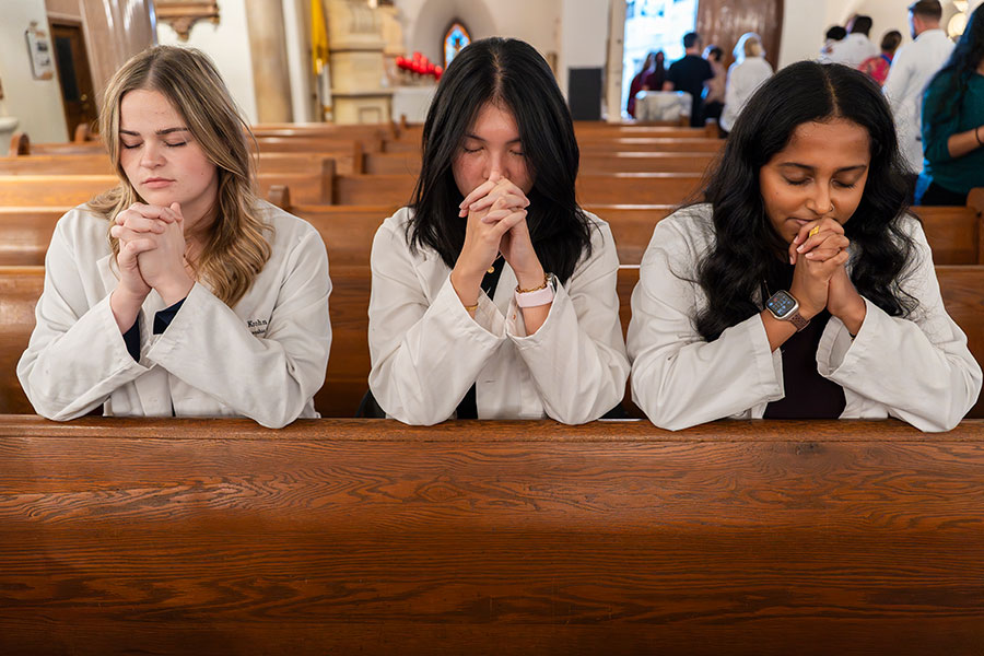 women in white coats at prayer